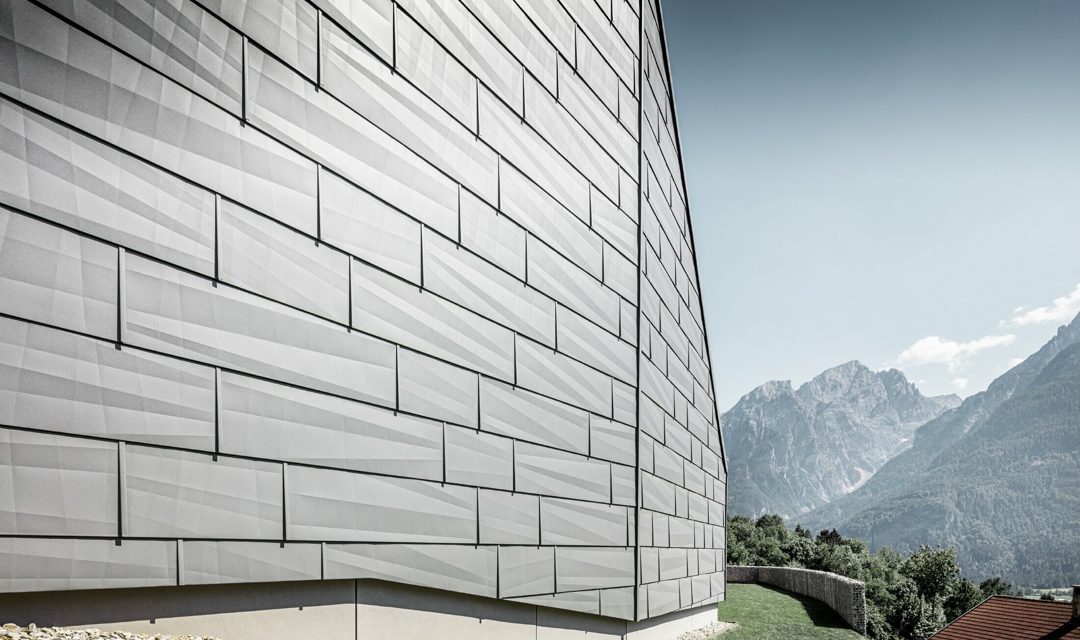 Powłoka zewnętrzna domu jednorodzinnego w austriackim Lienzu została pokryta panelem elewacyjnym FX.12 PREFA w kolorze jasnoszarym P.10.