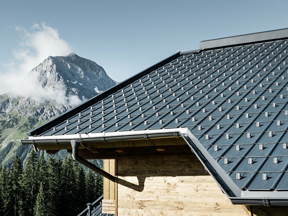 Dom drewniany w Bergen, dach jest pokryty dachówką PREFA w kolorze antracytowym z rynną dachową PREFA i elewacją drewnianą