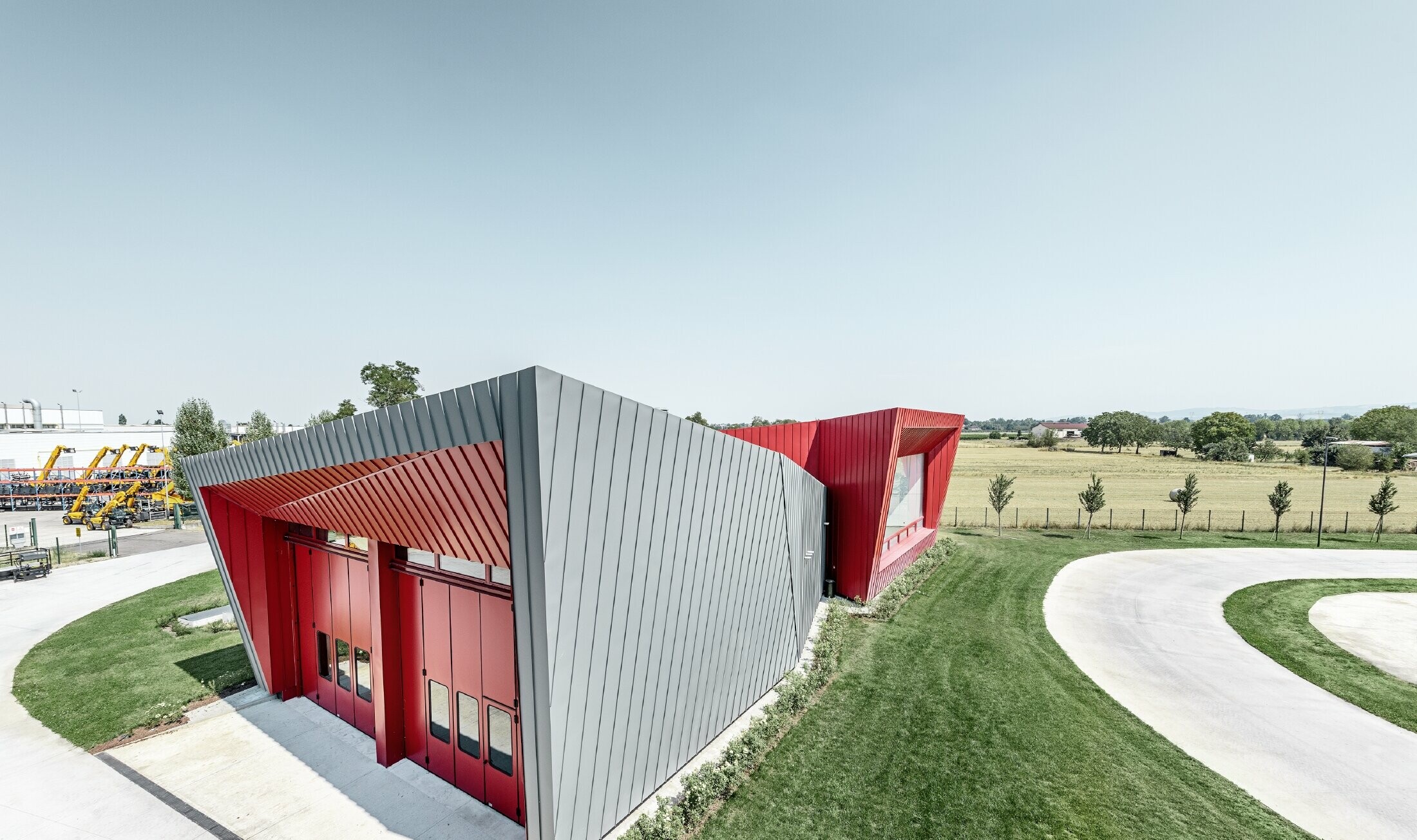 Nowoczesne centrum treningowe Dieci w Montecchio Emilia we Włoszech z trybuną z elewacją aluminiową PREFALZ w kolorze jasnoszarym i Falzonal w kolorze czerwonym karminowym