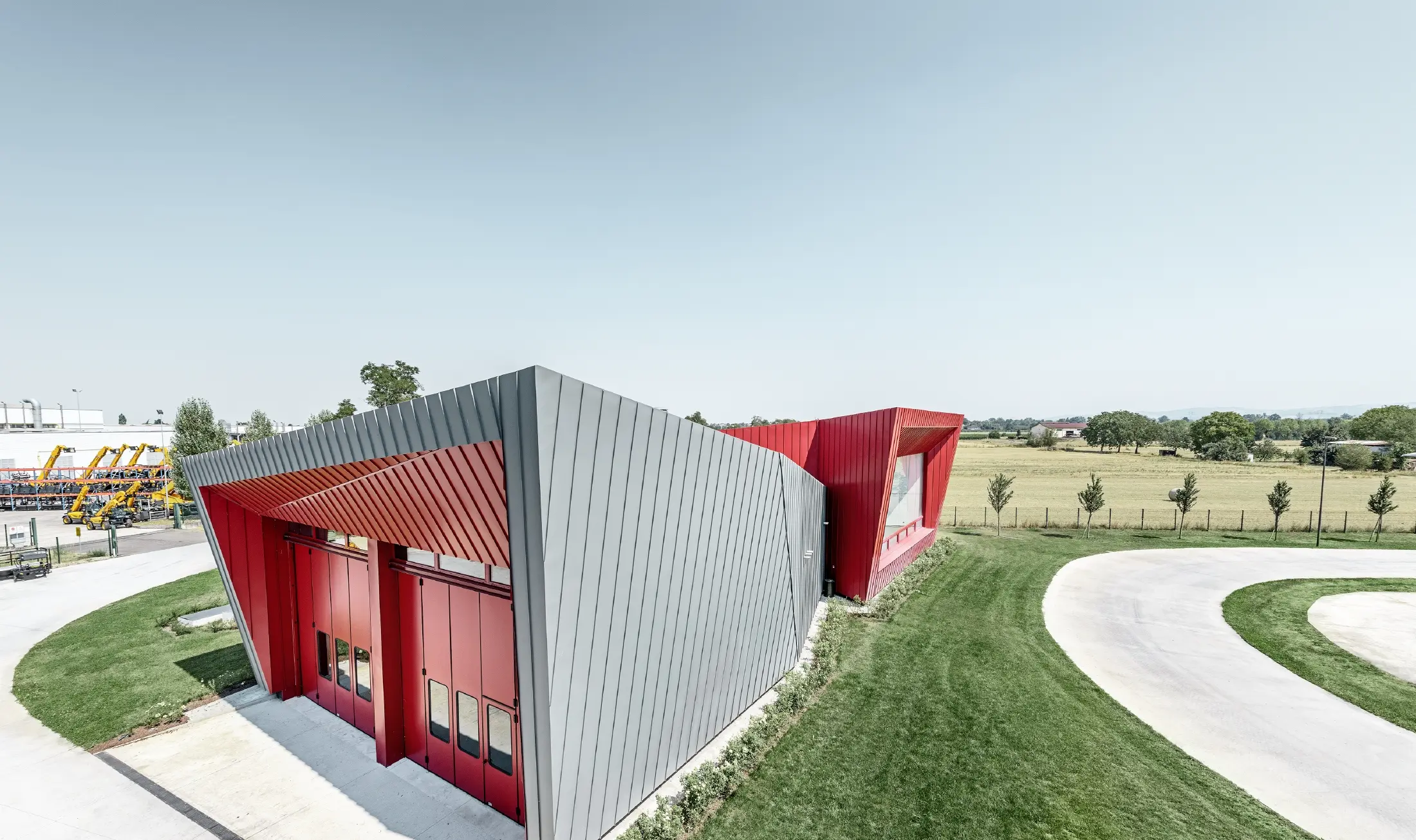Nowoczesne centrum treningowe Dieci w Montecchio Emilia we Włoszech z trybuną z elewacją aluminiową PREFALZ w kolorze jasnoszarym i Falzonal w kolorze czerwonym karminowym