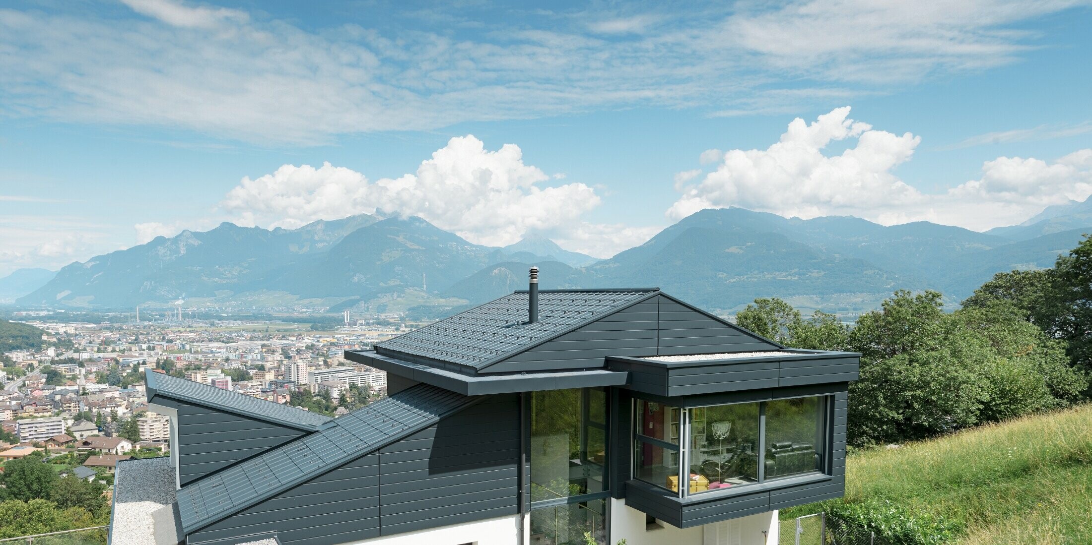 Die Fassade des Einfamilienhauses im Schweizer Ort Choëx ist mit PREFA Sidings in der Farbe P.10 Anthrazit bekleidet. Das Dach wurde mit den bewährten PREFA Dachplatten, ebenfalls in Anthrazit, gedeckt.