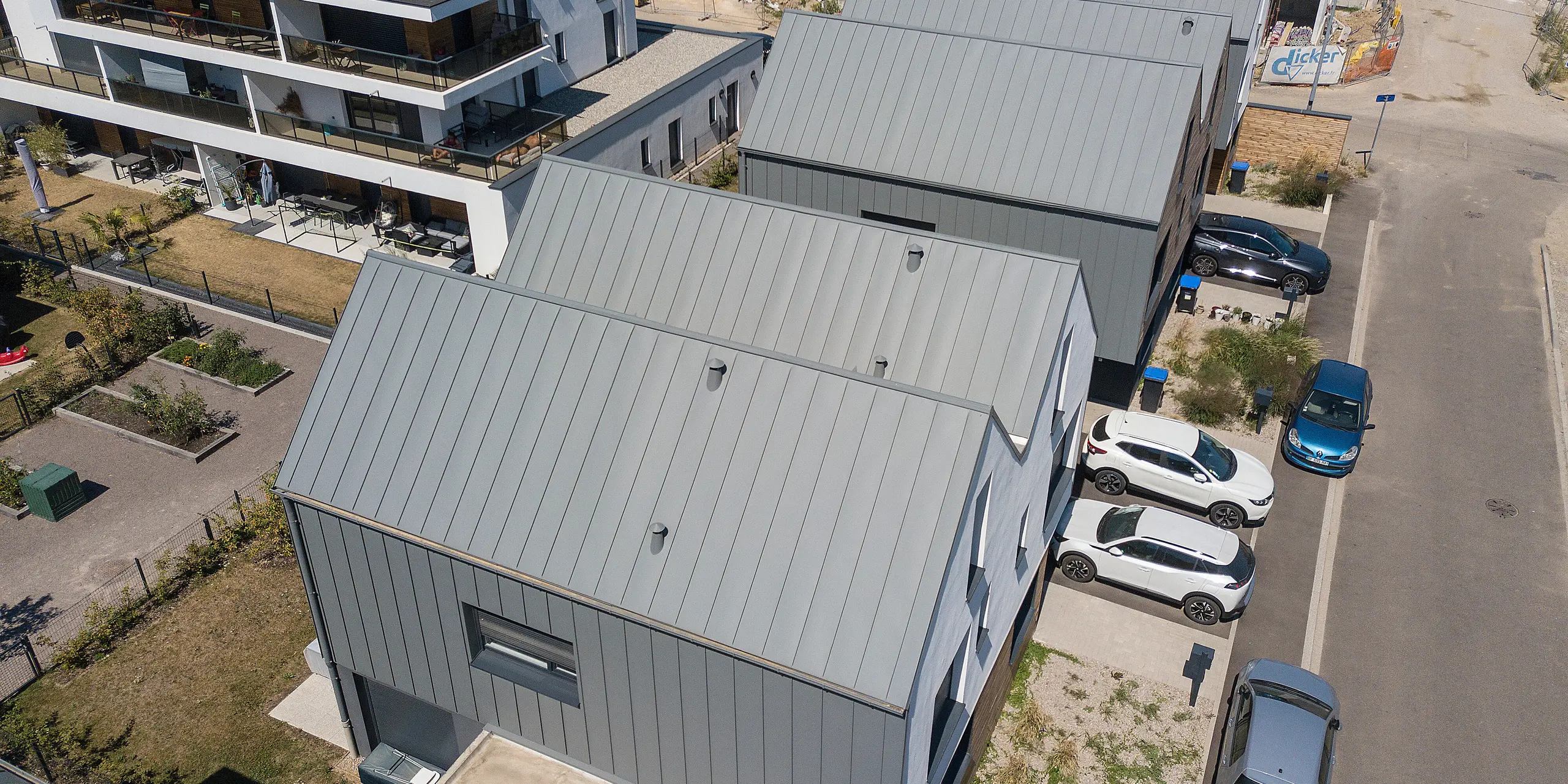PREFALZ in Hellgrau zieht sich über die Fassaden und Satteldächer einer Reihenhaus-Siedlung in Mundolsheim. Die einheitlichen Gebäudehüllen aus Aluminium schaffen ein harmonisches Gesamtbild.