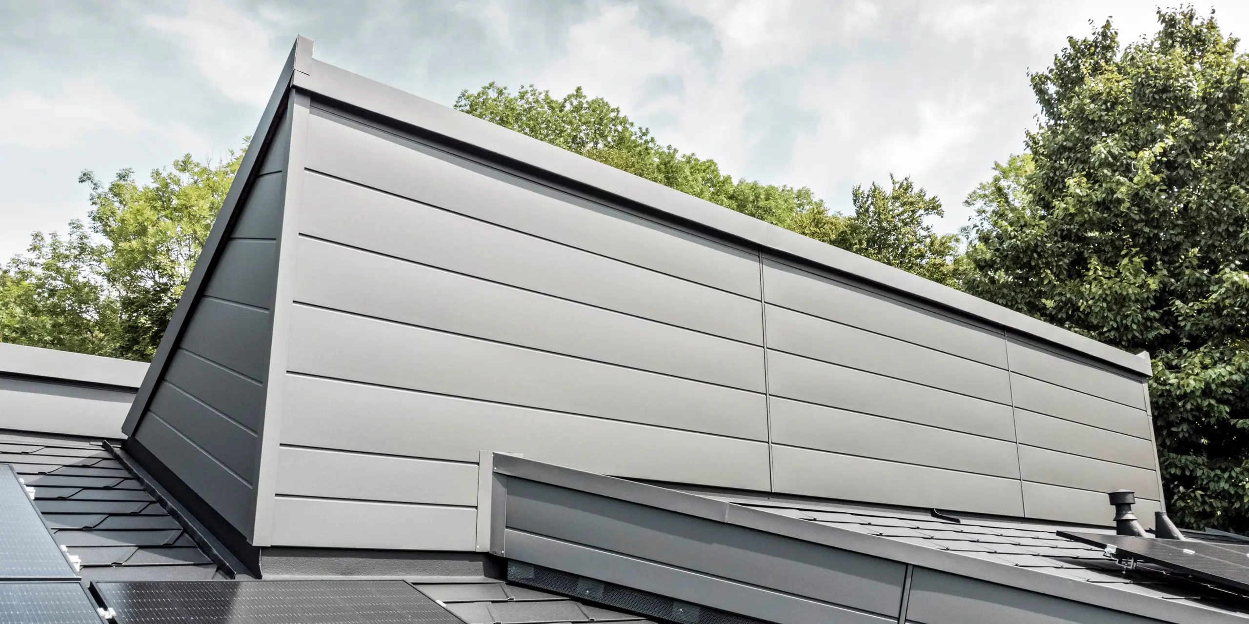 Ein Einfamilienhaus, das mit PREFA Dachschindeln DS.19 in schwarz eingedeckt wurde. Für Teile der Fassade wurden PREFA Sidings in P.10 dunkelgrau verwendet. 