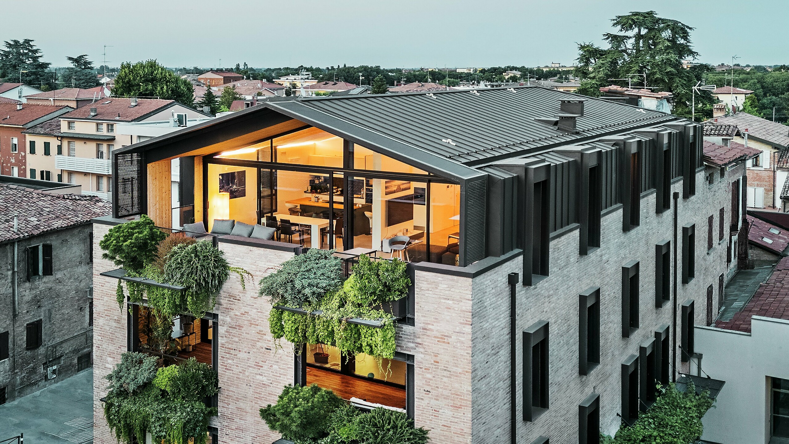 Zrównoważony budynek mieszkalny we Włoszech z dachem aluminiowym PREFALZ i zieloną fasadą z cegły.