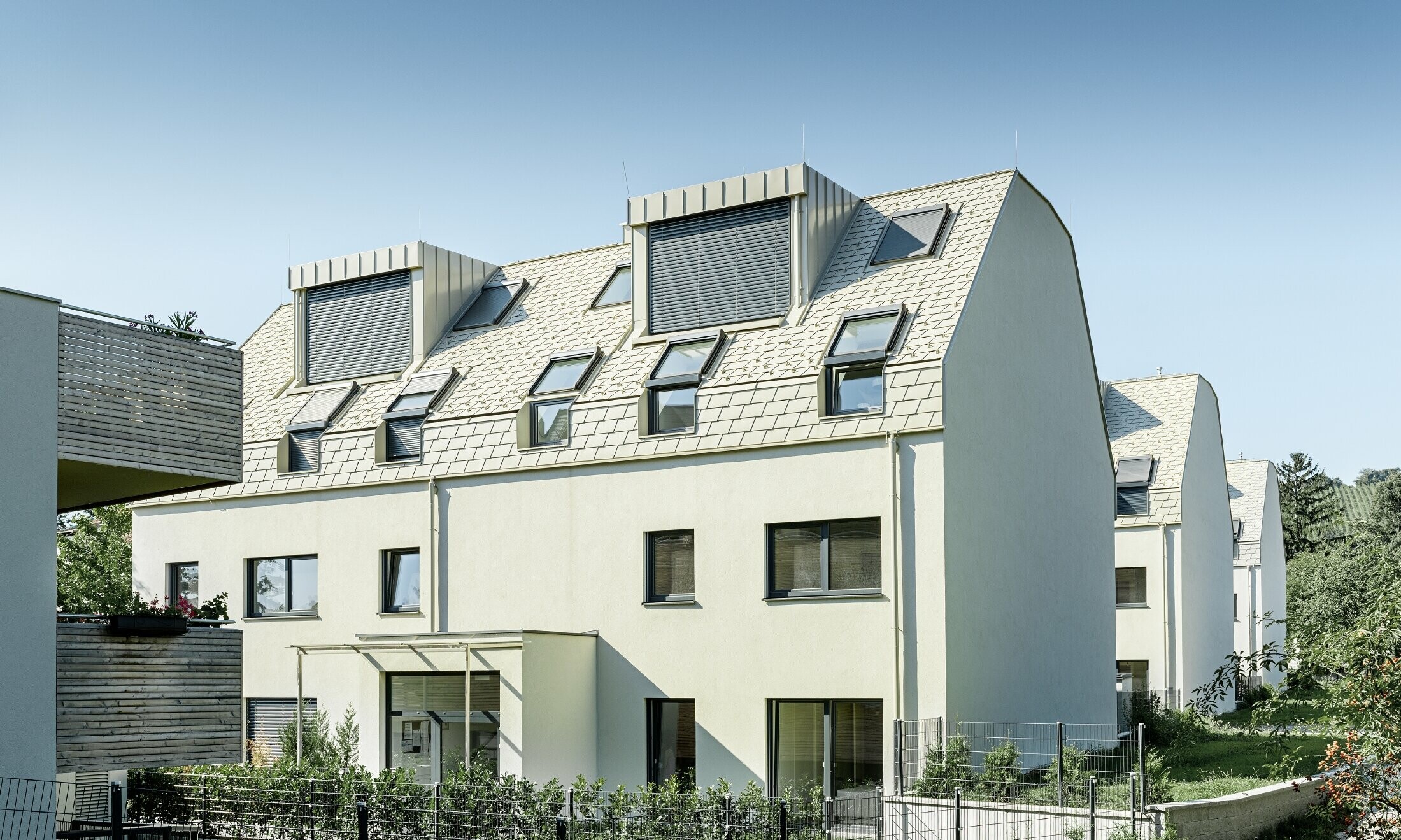 Nowe osiedle mieszkaniowe z dużymi powierzchniami dachowymi pokrytymi aluminium i wieloma oknami połaciowymi