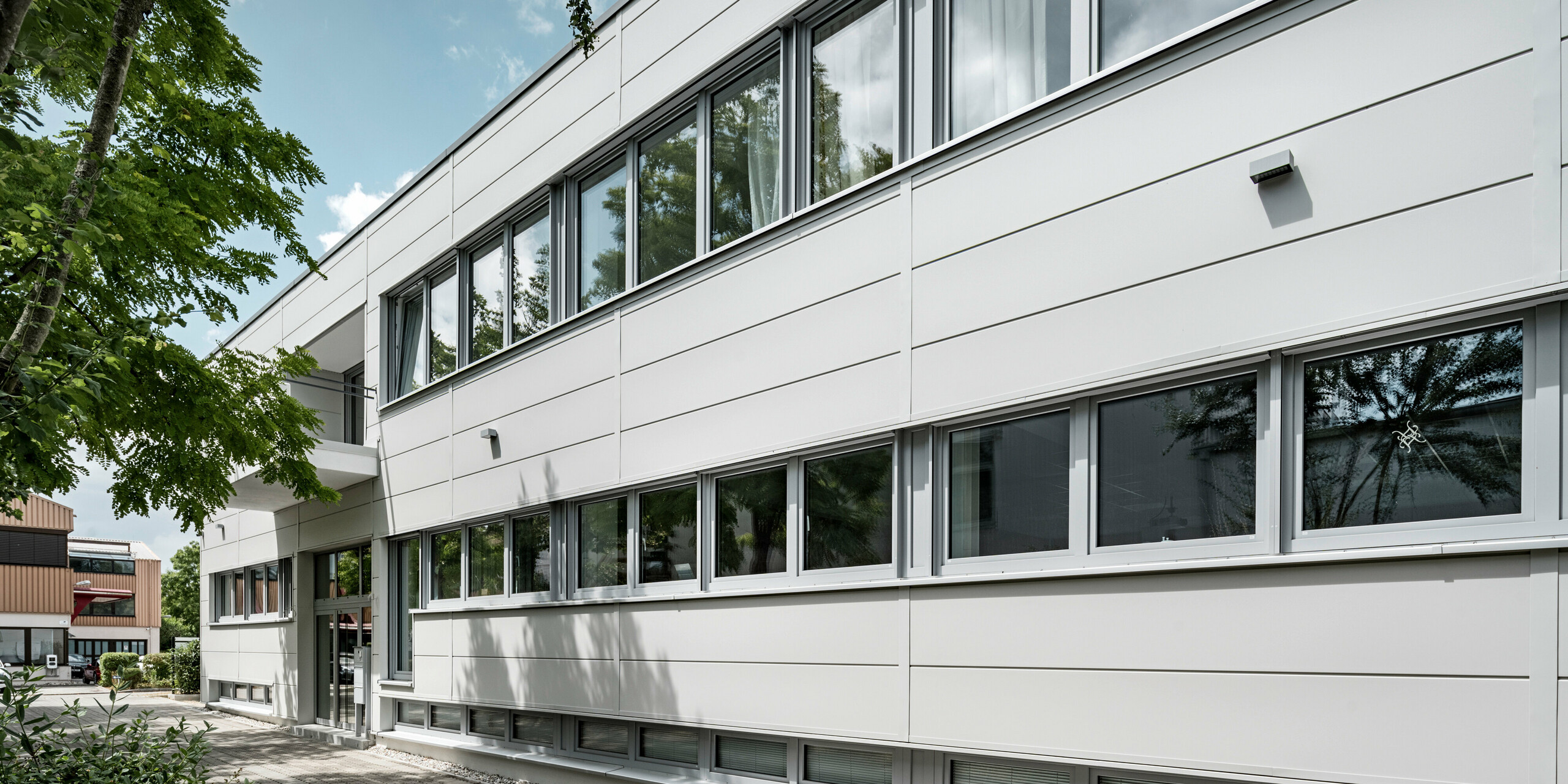 Großformatige PREFA Sidings umhüllen ein Firmengebäude in Oberschleißheim (Deutschland). Die extrabreiten Fassadenelemente aus Aluminium sind in der Farbe Prefaweiß gehalten.