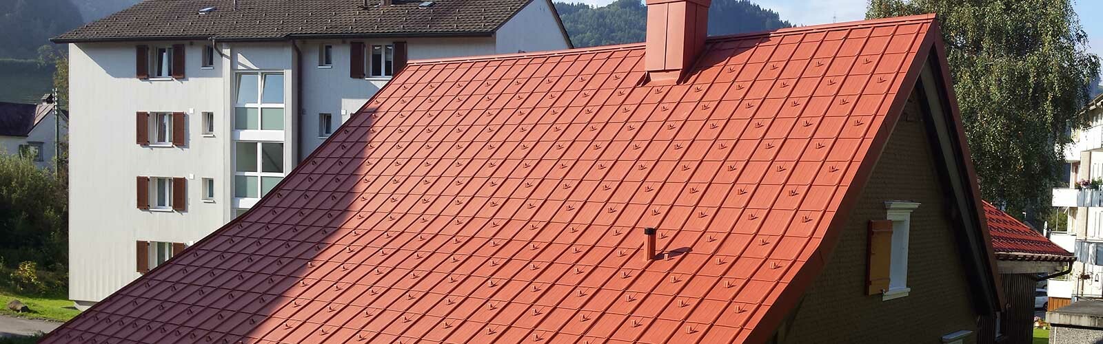 Einfamilienhaus mit Walmdach aus Aluminiumschindeln von PREFA in Ziegeloptik mit Schneestoppern.