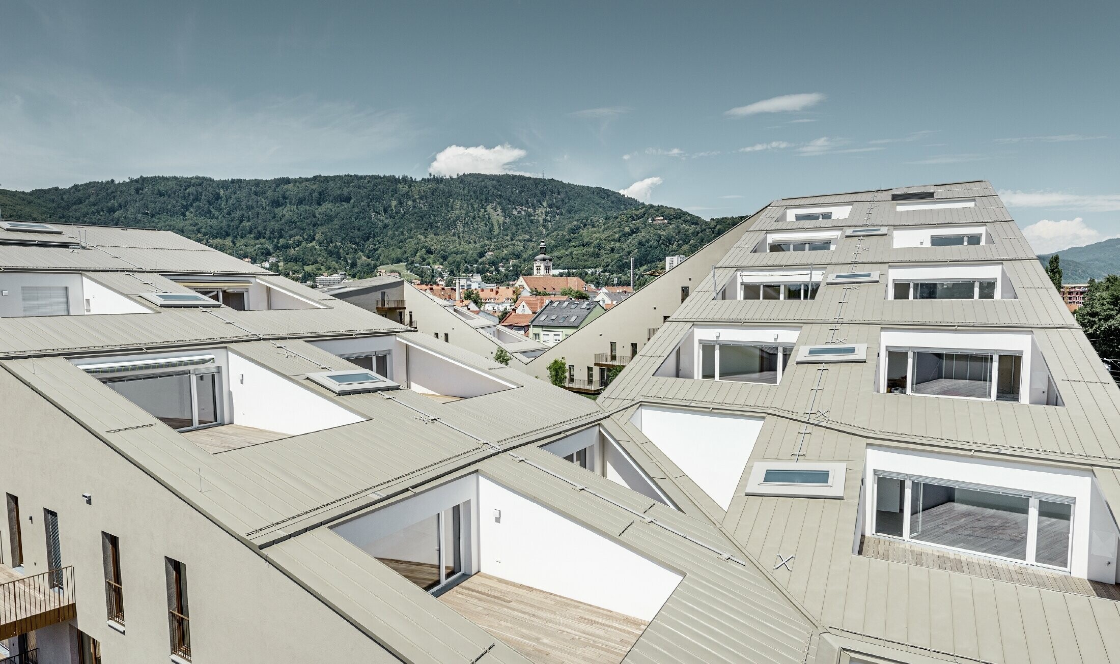 Osiedle mieszkaniowe w Grazu z płaskimi dachami, zintegrowanymi tarasami i wielkopowierzchniowymi oknami, z dachem Prefalz w kolorze specjalnym broncemetallic