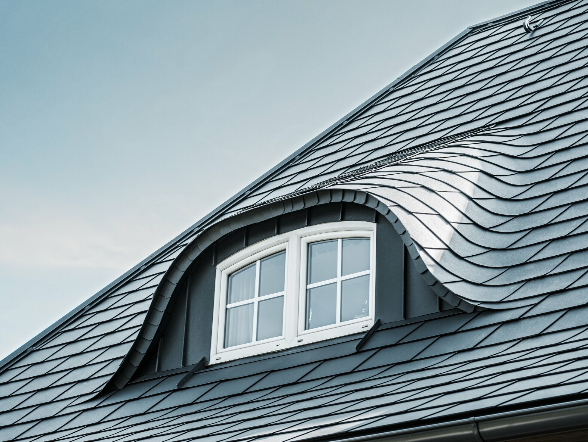 Nowo wyremontowany dach z łukowatą lukarną z oknem, pokryty aluminiową dachówką łupkową PREFA w kolorze P.10 antracyt 