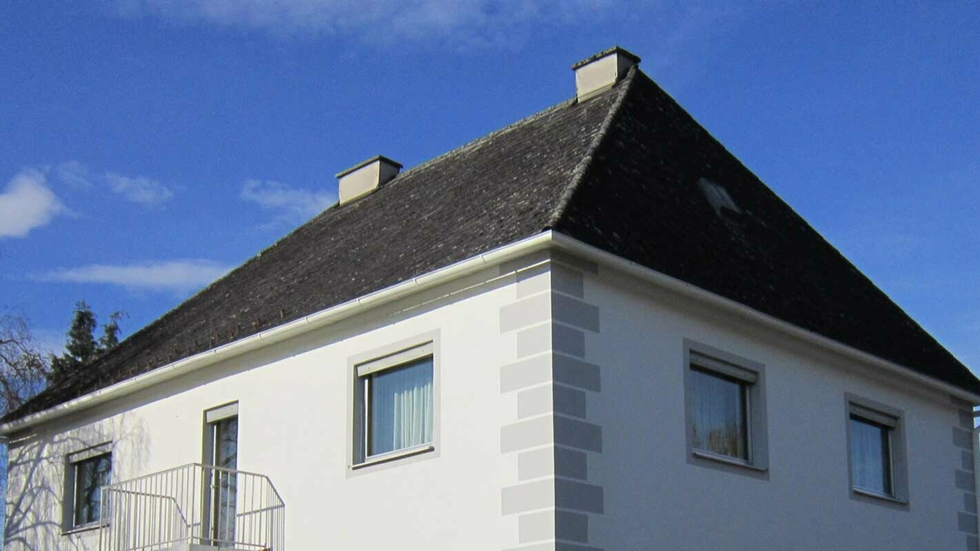 Dom z dachem czterospadowym przed modernizacją dachu z blachą Prefalz i płytą dachową PREFA w Austrii