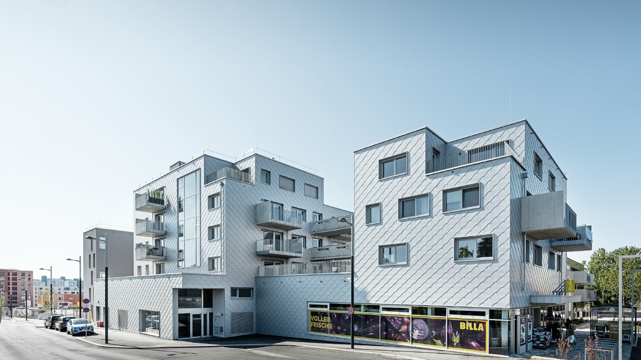 Osiedla mieszkaniowe z dachami płaskimi i okładziną rombem elewacyjnym PREFA 44 × 44 w kolorze srebrny metalik