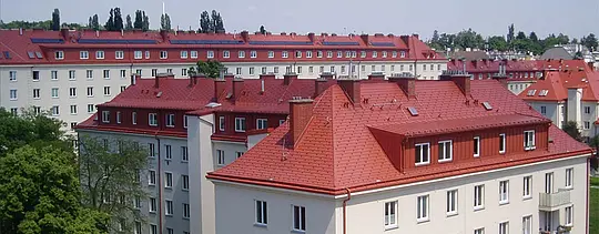 Zdjęcie domów mieszkalnych Hugo Breitner Hof w Wiedniu. Dachy pokryto dachówką łupkową PREFA w kolorze ceglastym.