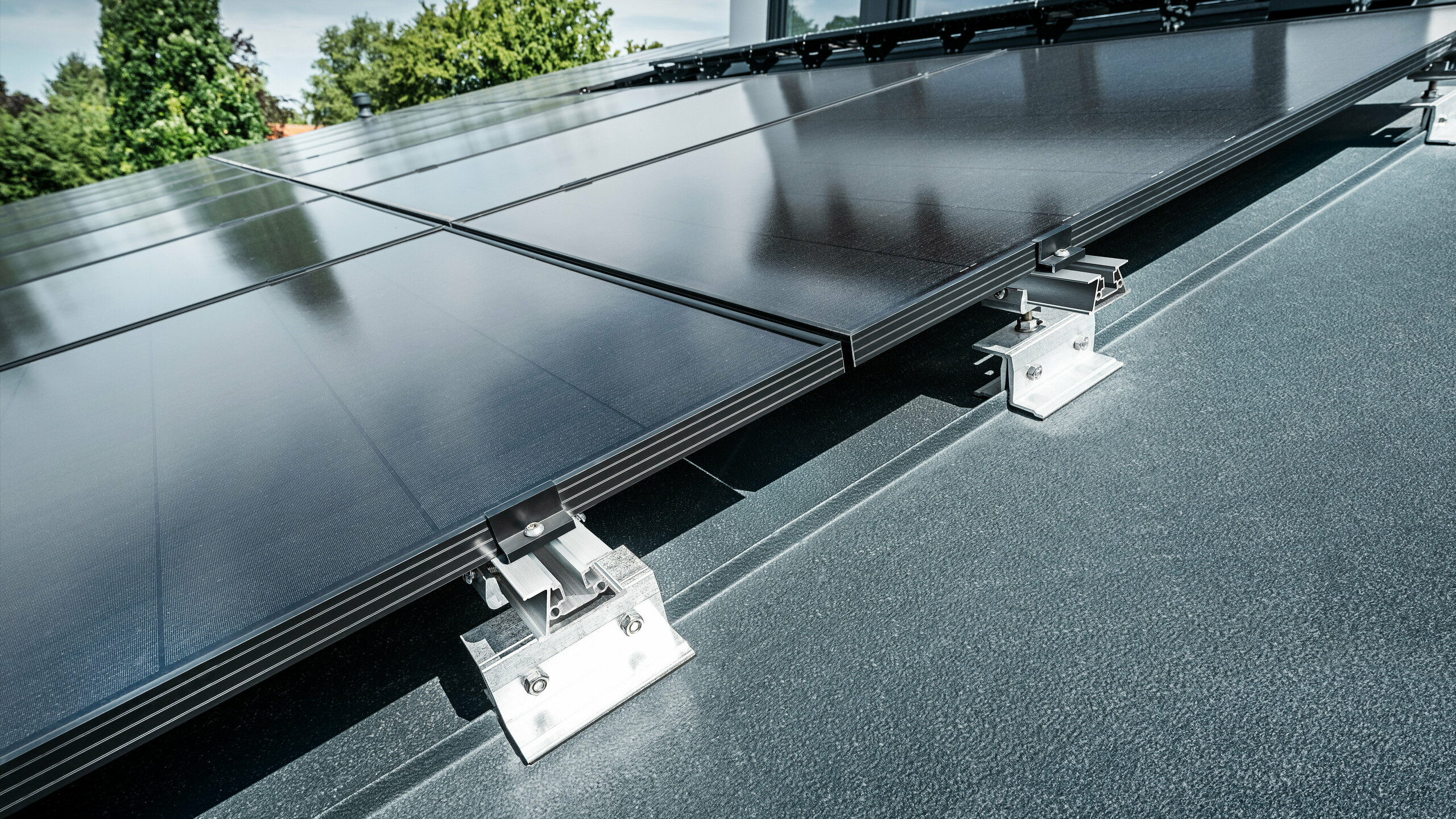 Zbliżenie wspornika solarnego PREFA PREFALZ Vario na dachu z rąbkiem stojącym w kolorze antracytowym 