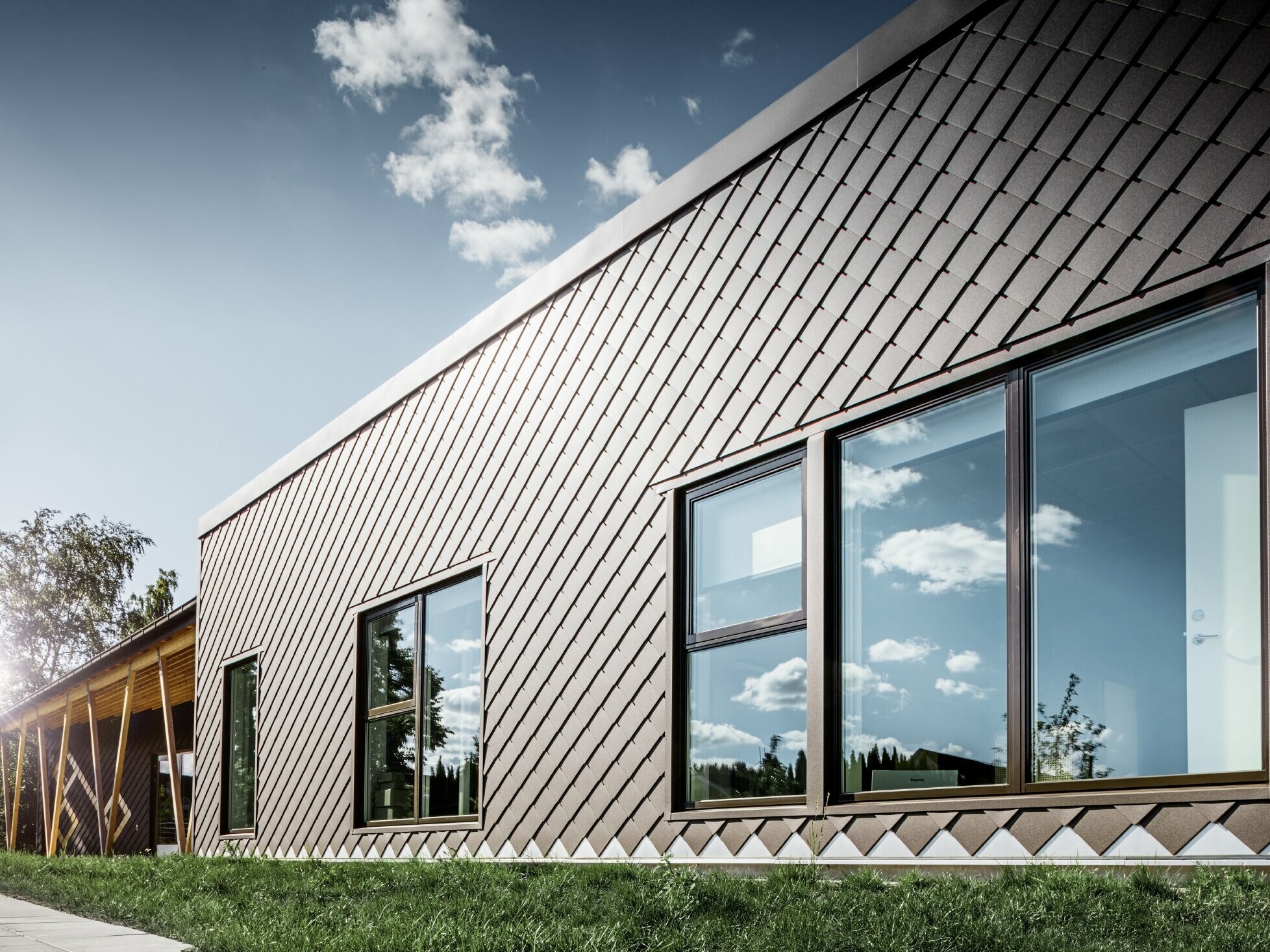 To zdjęcie przedszkola w Sztokholmie przedstawia nową elewację z dużymi powierzchniami okiennymi i dachem płaskim. Elewacja została obłożona rombem fasadowym 20 × 20 w kolorze brązowym.