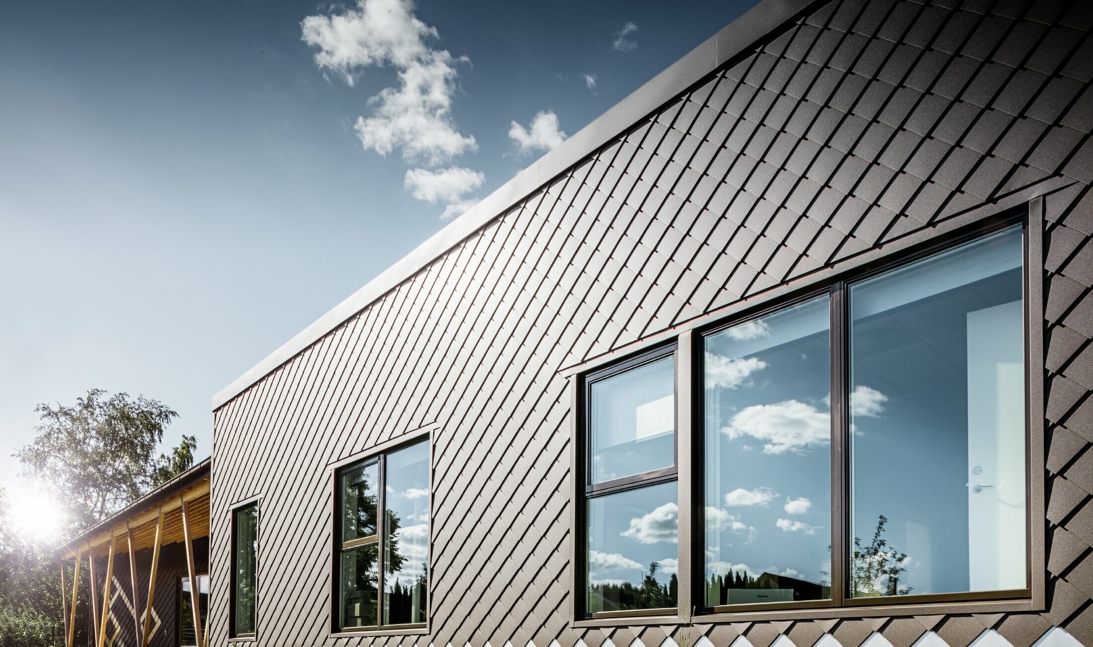 To zdjęcie przedszkola w Sztokholmie przedstawia nową elewację z dużymi powierzchniami okiennymi i dachem płaskim. Elewacja została obłożona rombem fasadowym 20 × 20 w kolorze brązowym.
