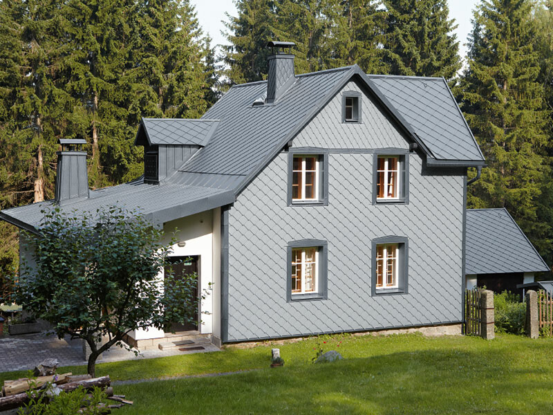 Dom jednorodzinny w lesie z odporną na warunki pogodowe elewacją aluminiową PREFA w jasnoszarym kolorze.