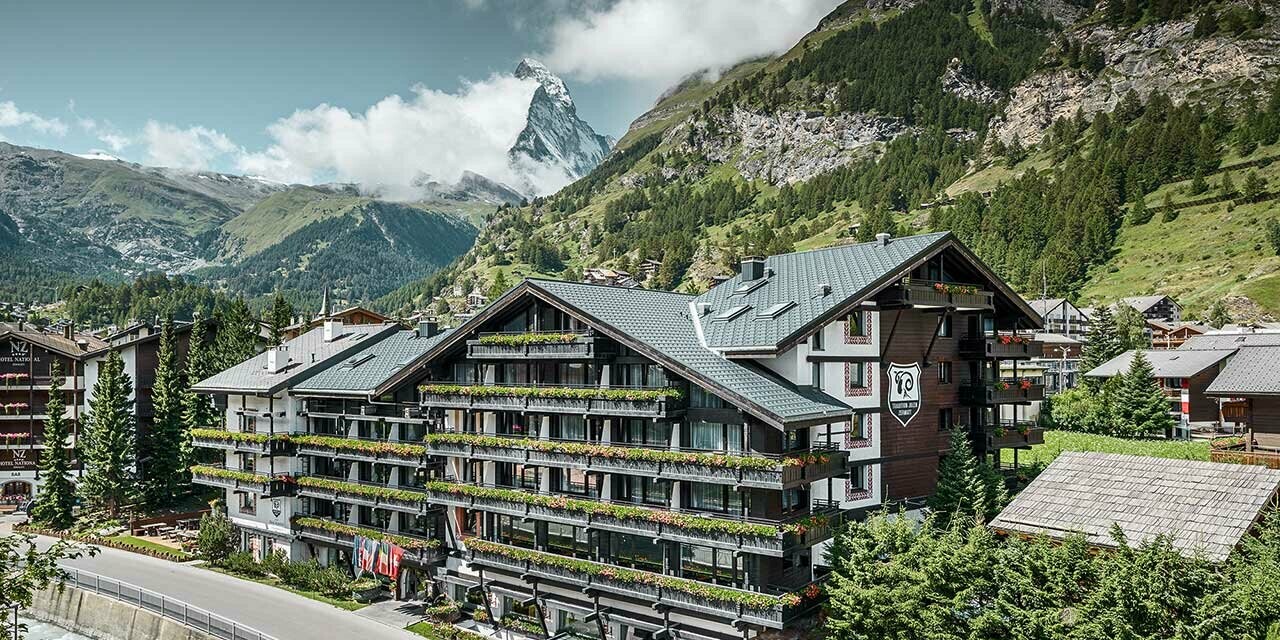 Hotel Alpenhof w Zermatt ze szczytem Matterhorn w tle, balkony, ciemna elewacja drewniana i aluminiowy dach PREFA w kolorze antracytu