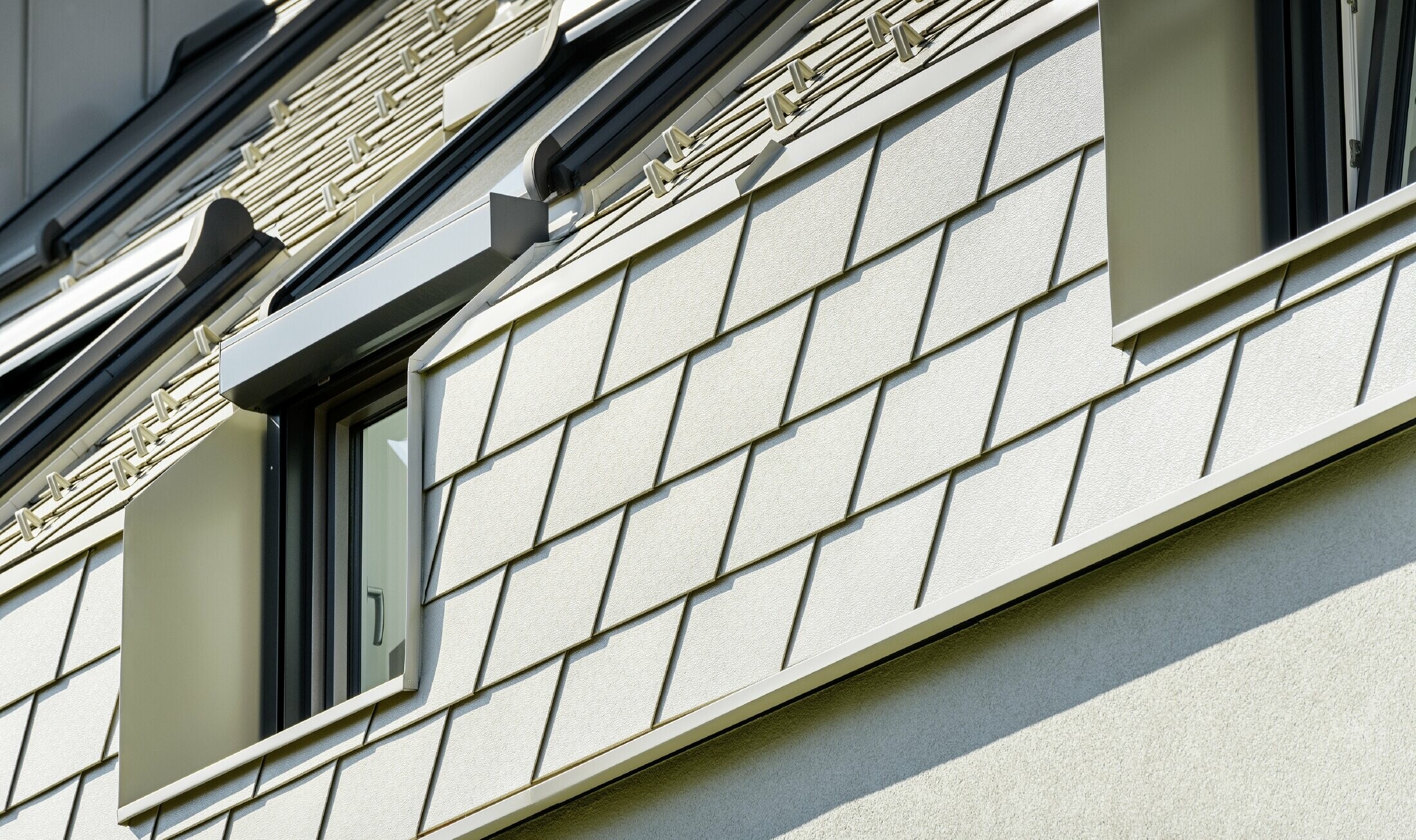 Nowe osiedle mieszkaniowe z dużymi powierzchniami dachowymi pokrytymi aluminium i wieloma oknami połaciowymi