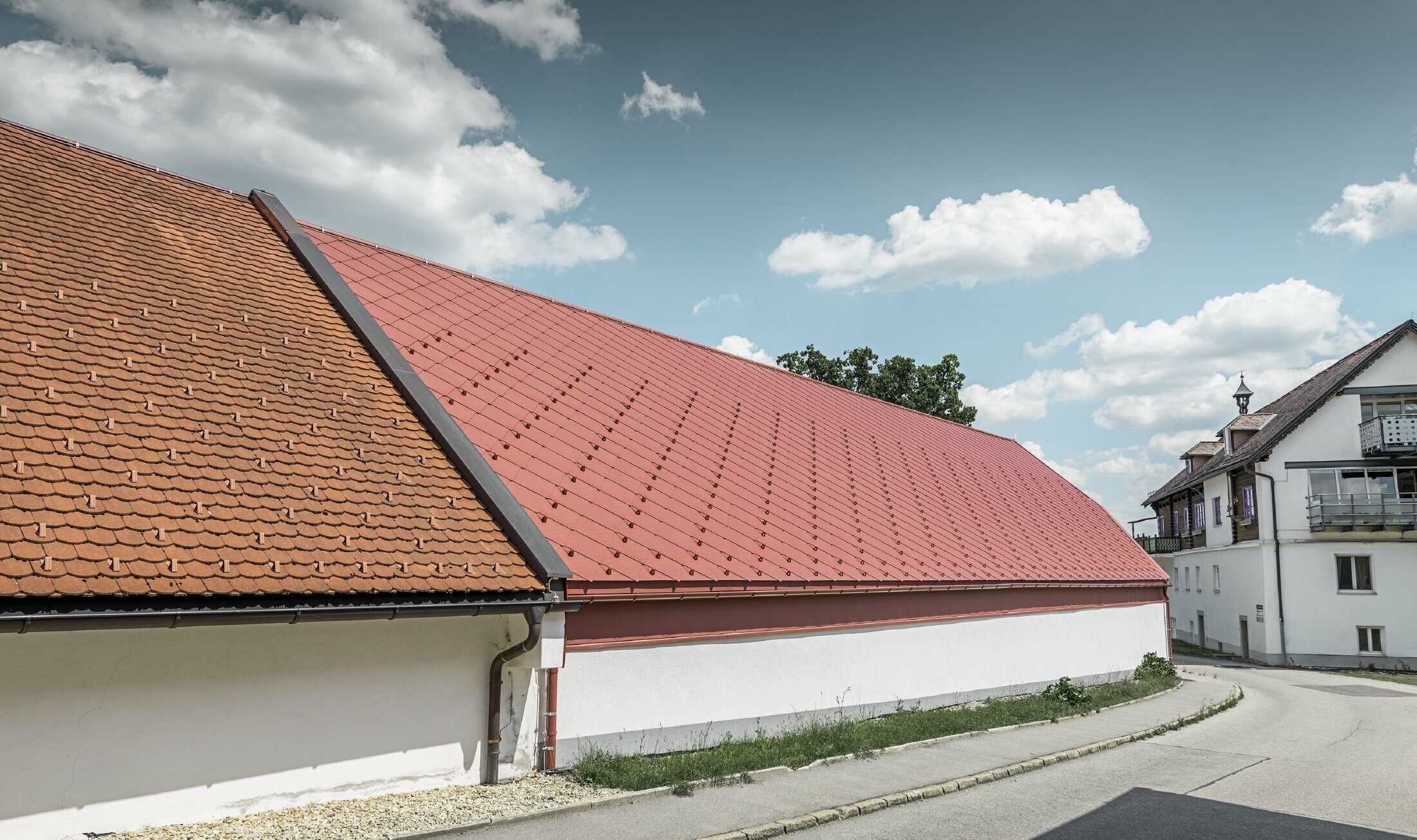 Widok z zewnątrz Kerzenwelt w Schlägl; dach został pokryty wielkopowierzchniowym rombem aluminiowym 44 × 44 PREFA w kolorze czerwonym tlenkowym.