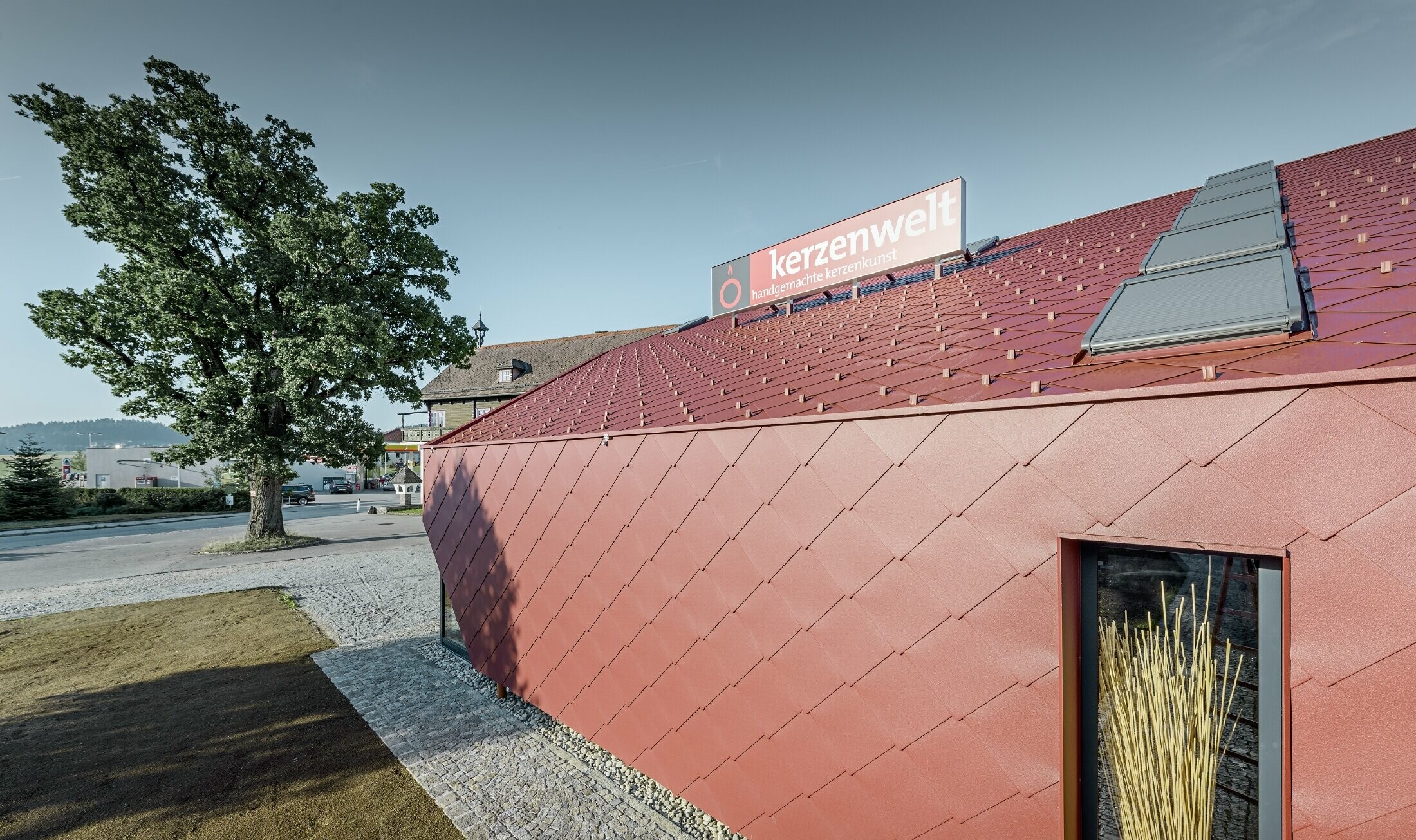 Salon świec Kerzenwelt w Schlägl został w całości obłożony nowymi rombami PREFA. Krycie dachu i poszycie elewacji wykonano z rombu 44 × 44 w kolorze czerwonym tlenkowym.