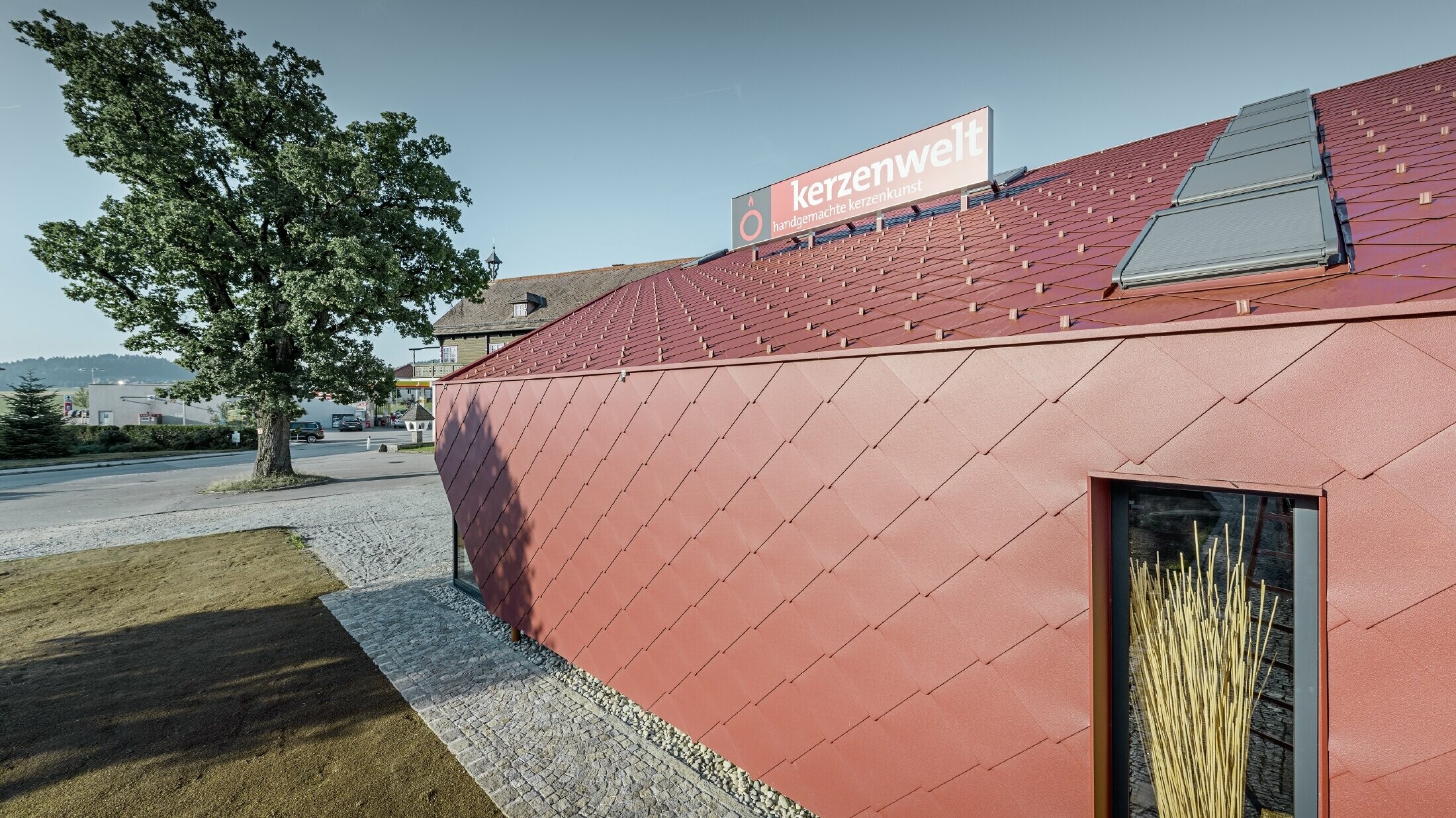 Salon świec Kerzenwelt w Schlägl został w całości obłożony nowymi rombami PREFA. Krycie dachu i poszycie elewacji wykonano z rombu 44 × 44 w kolorze czerwonym tlenkowym.