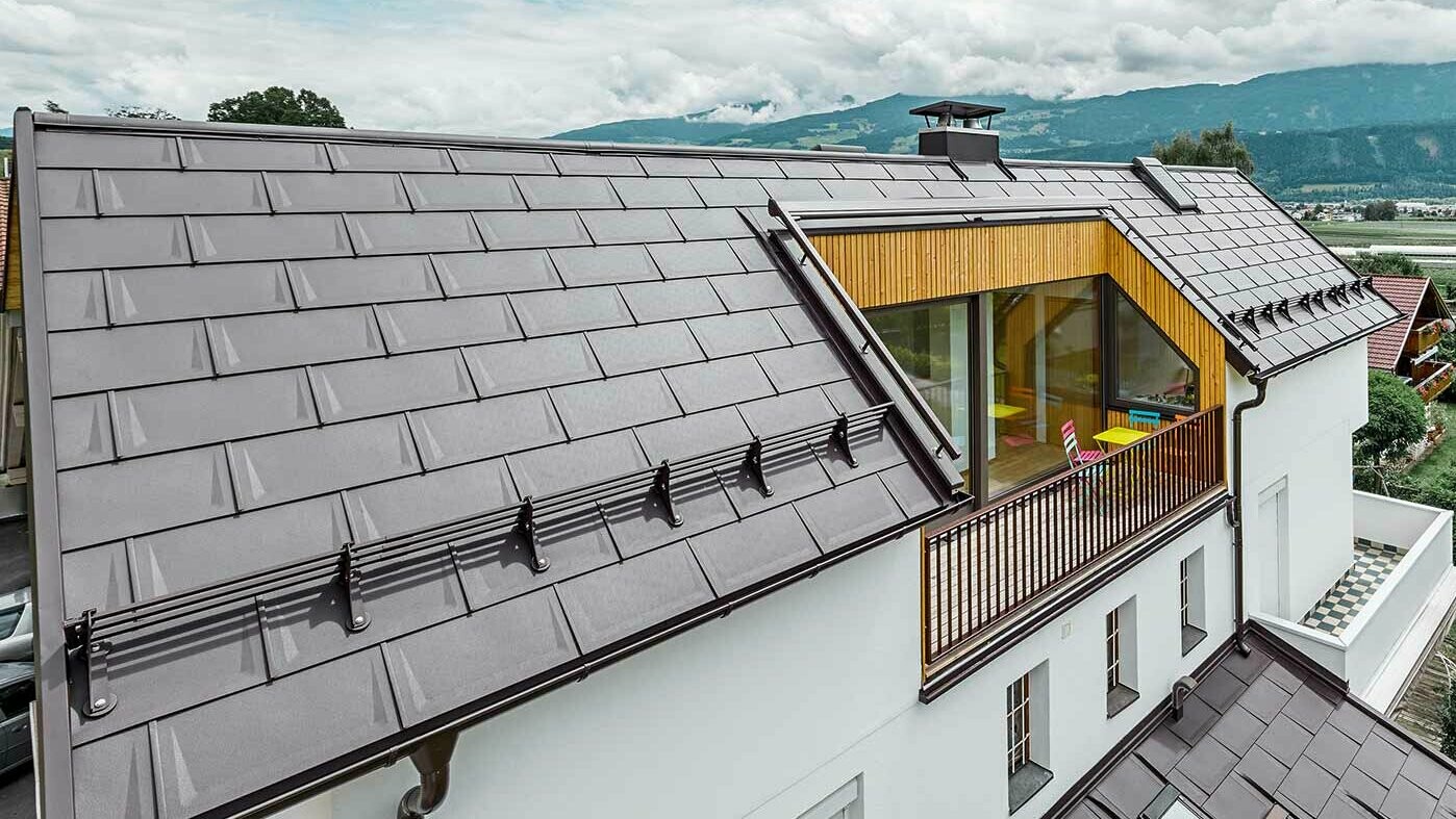 Dom wielorodzinny z przestronną loggią — dach jest kryty płytą dachową PREFA R.16 w kolorze brązowym orzechowym.