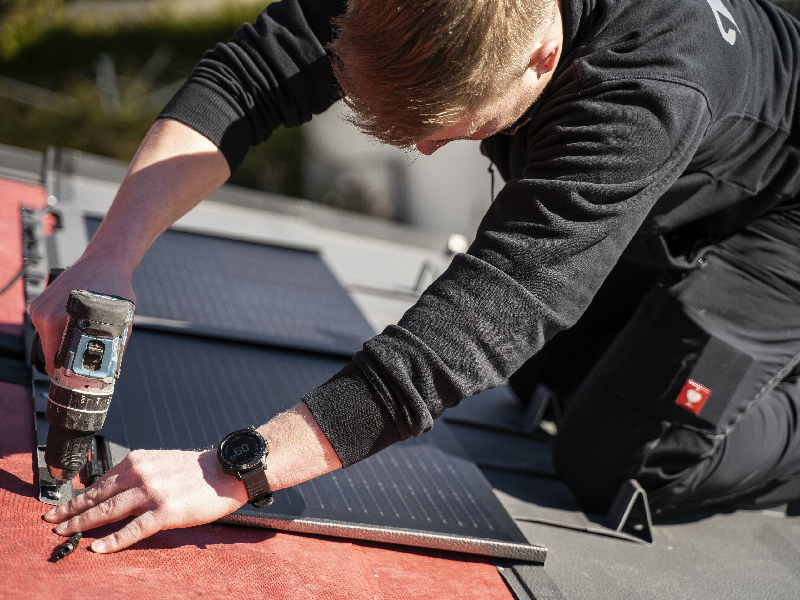 Pracownik PREFA podczas układania dachówki solarnej.