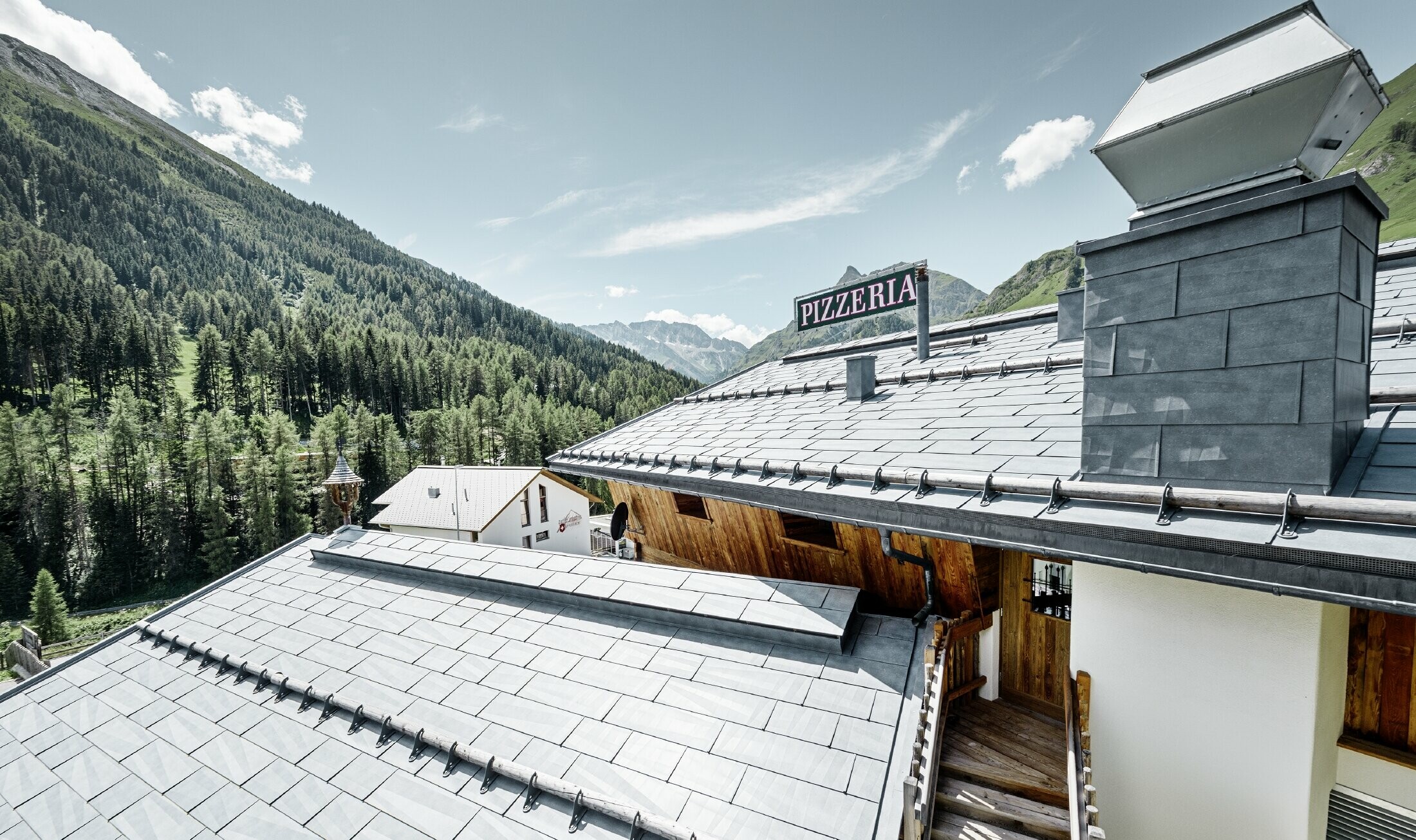 Restauracja Almrausch z górami w tle, na dachu panele dachowe PREFA FX.12 w kolorze kamiennym szarym ze śniegołapami