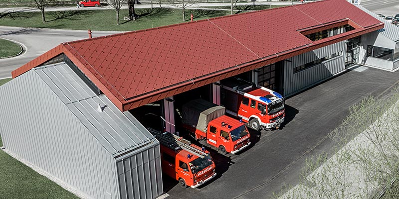 Remiza strażacka firmy PREFA w miejscowości Marktl z dachem wykonanym z czerwonej dachówki romb oraz dachem i elewacją na rąbek stojący w kolorze srebrny metalik. Więcej informacji na temat klas ogniowych znajdziesz tutaj.