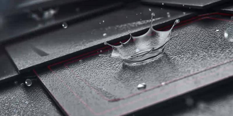 Zbliżenie rombu dachowego PREFA z kroplami wody na powierzchni. Powierzchnia płyty dachowej to Stucco, a kolor antracyt. 