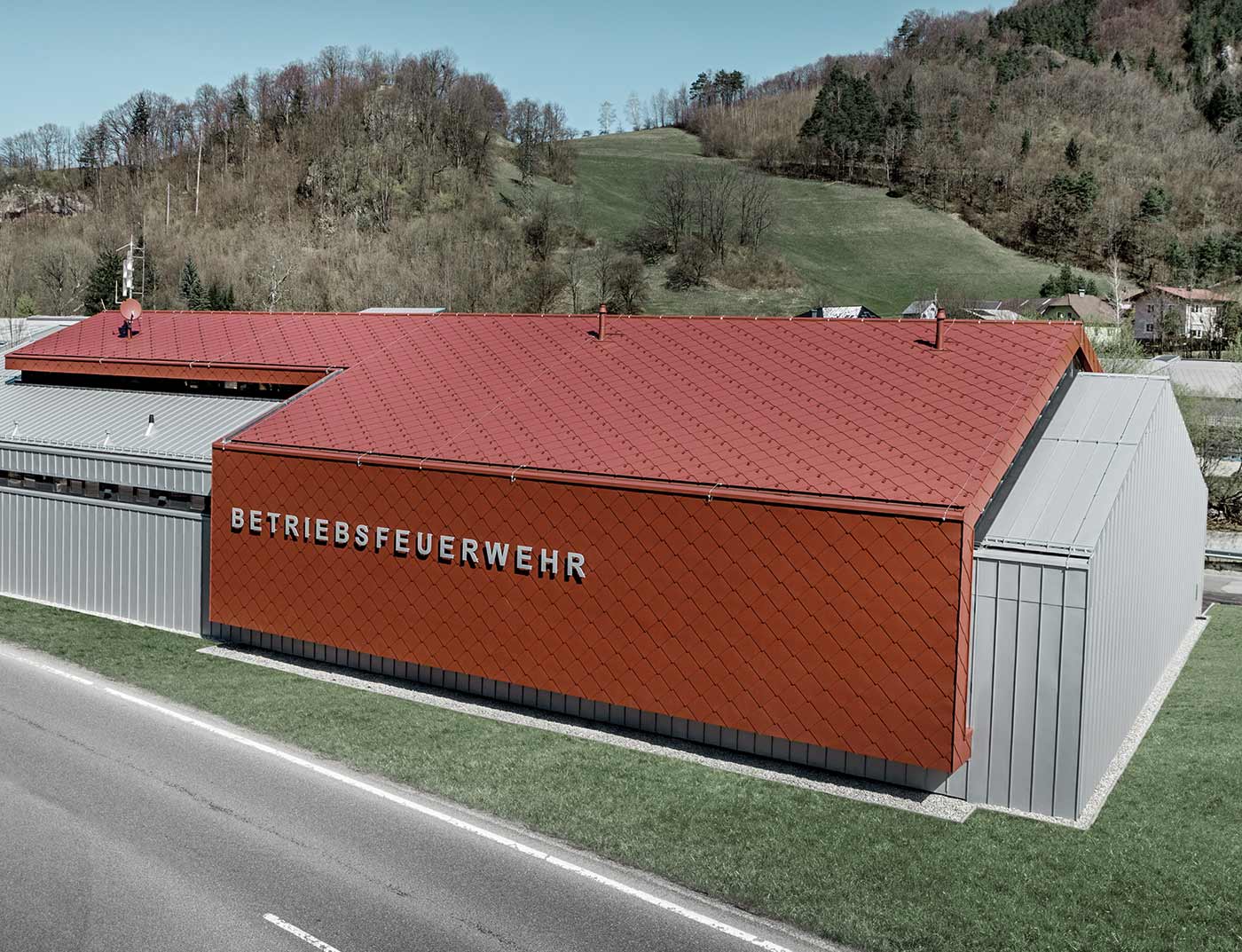 Dachówka rombowa PREFA 44 x 44, czerwony tlenkowy, referencja Nowy budynek zakładowej straży pożarnej firm PREFA i Neuman Aluminium został obłożony nowymi dachówkami rombowymi i rombowymi płytami ściennymi 44 x 44 w kolorze P.10 czerwony tlenkowy i blachą Prefalz w kolorze srebrny metallic.
